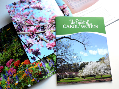 Photograph of several annual reports for Carol Woods: one full cover with "The Spirit of Carol Woods" in white against green at the top and a picture of cottages, cherry trees, and a blue sky at the bottom, all with a white swoosh between; a close-up photo of colorful zinnias; and a close-up photo of a redwood blooming next to a plum and white table of contents.