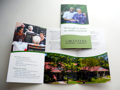 Photograph of a brochure for Carol Woods including photographs of an older African-American couple on the cover and a younger African-American women at a table with older adults inside. A photograph of a Carol Woods cottage with a flowering garden is also inside. Text and accents are black and green.