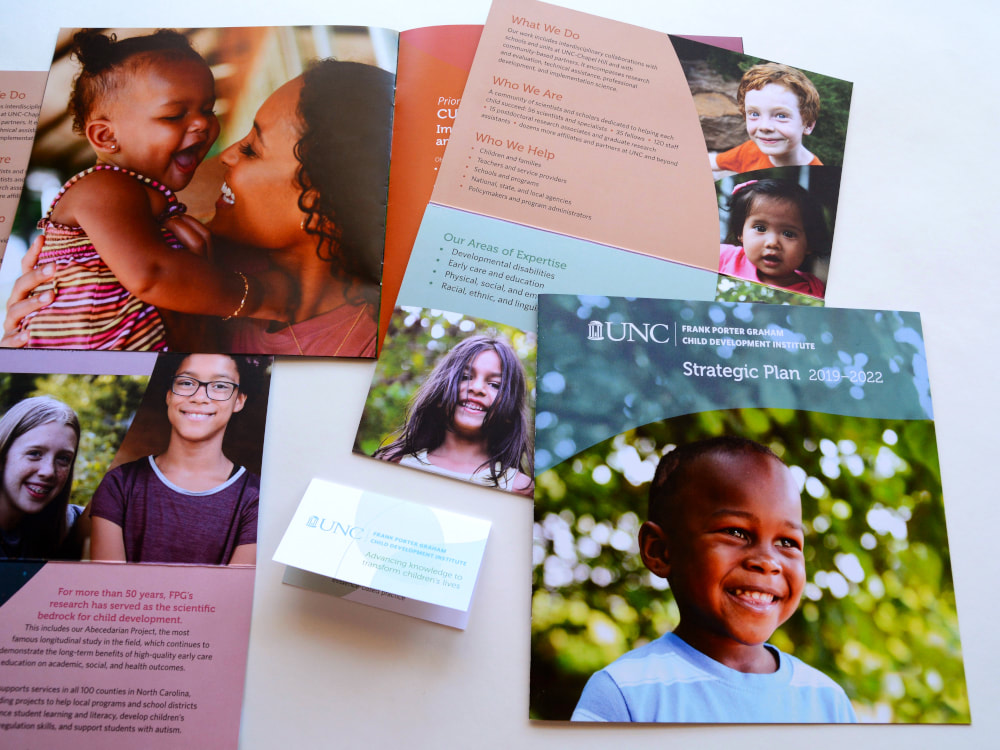 Various printed pieces include a square booklet; a large, vertical brochure; and a folding information card. Orange, purple, red, Carolina blue, and green colors and swooping shapes complement photos of smiling children.